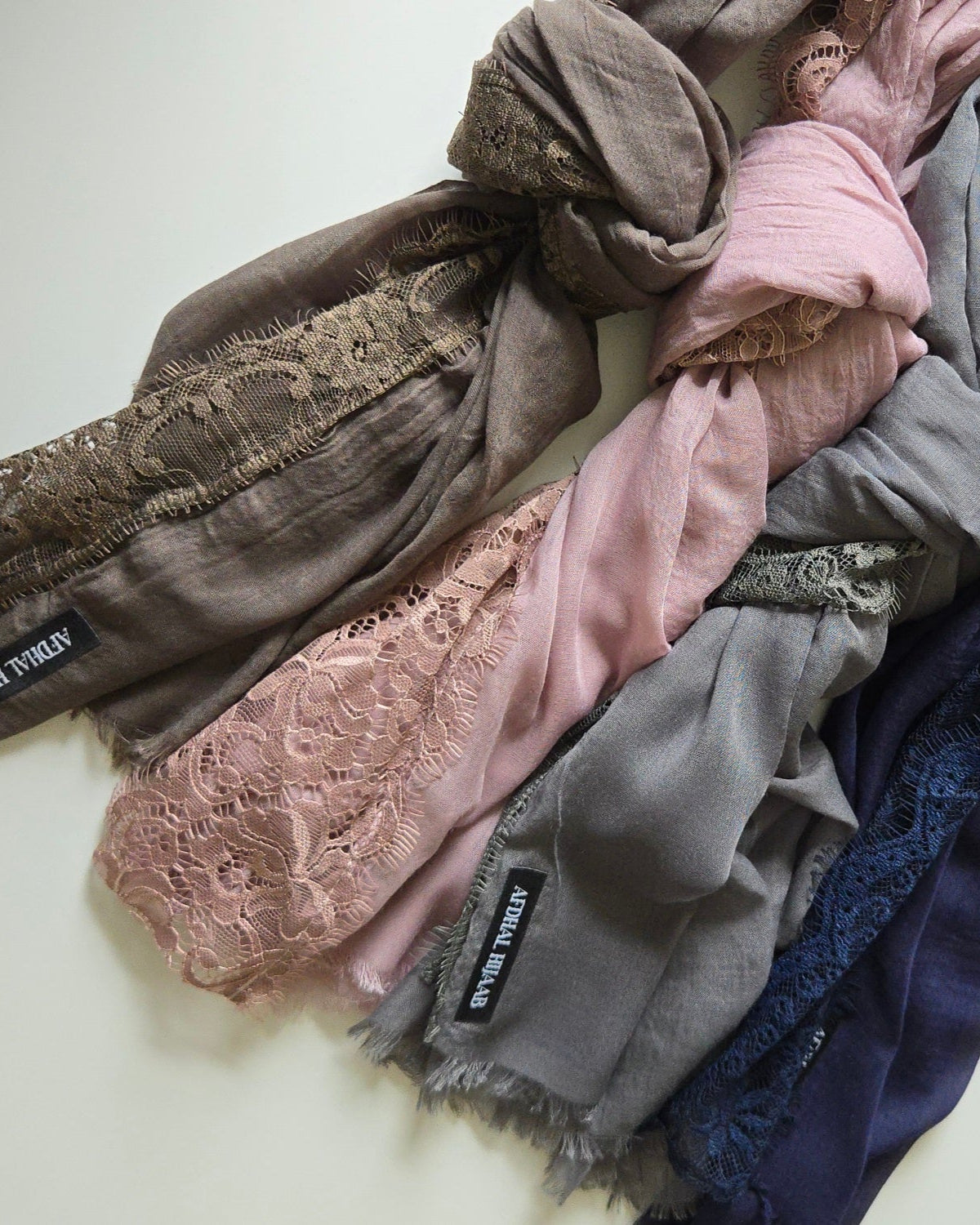 Stack of lace hijabs in various colors on a light background