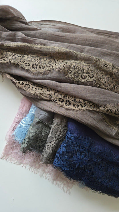 Stack of lace-trimmed fabrics in various colors on a white background