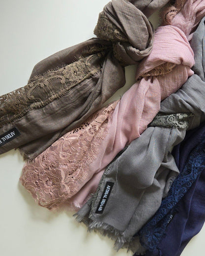 Stack of lace hijabs in various colors on a light background
