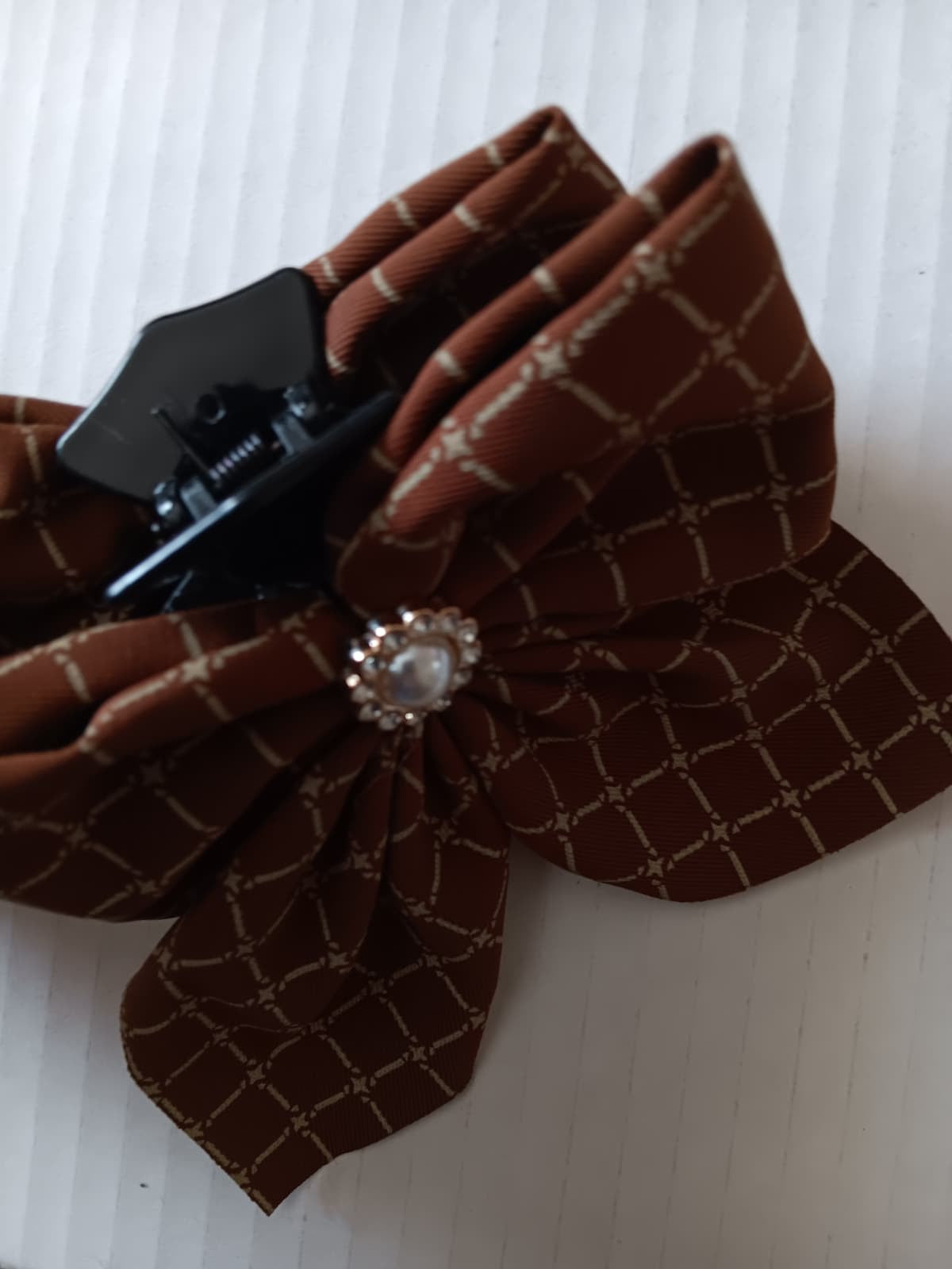 Brown textured bow with a decorative clasp on a white background