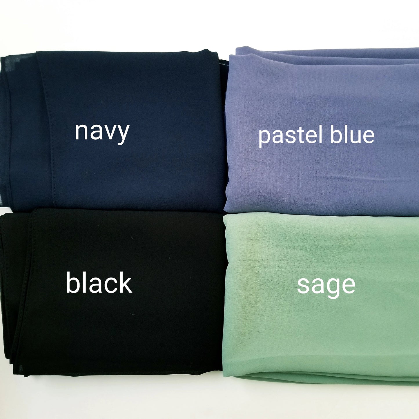 Four folded chiffon hijabs in navy, pastel blue, black, and sage on a white background.