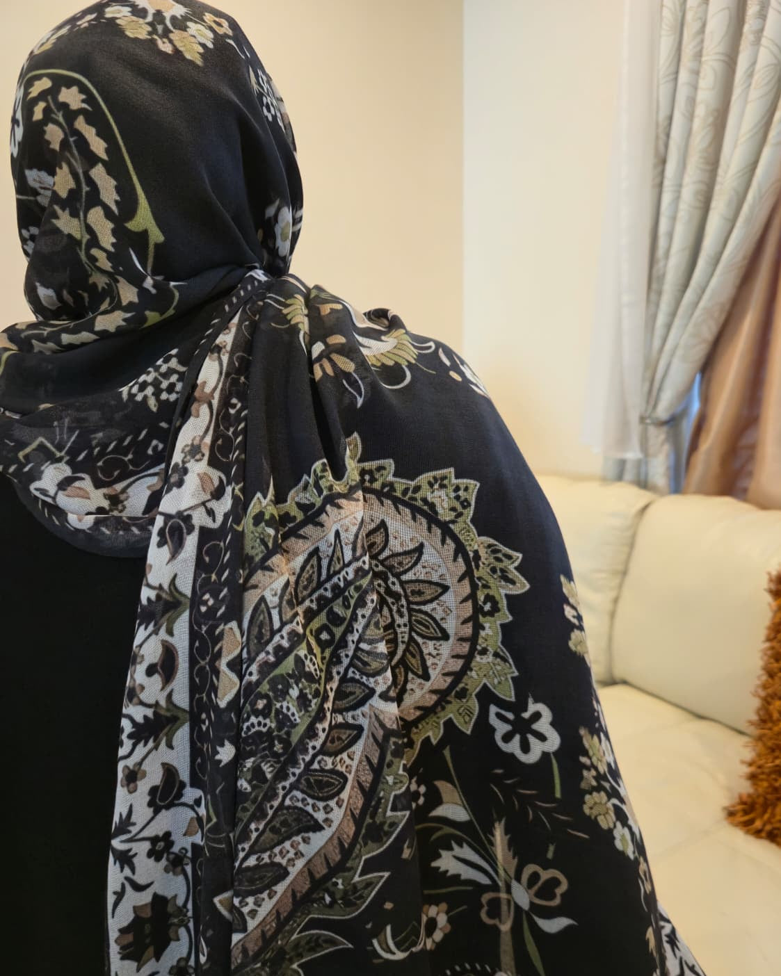 Person wearing a black floral patterned hijab with a blurred background