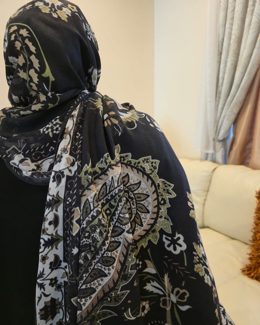 Person wearing a black floral patterned hijab with a blurred background
