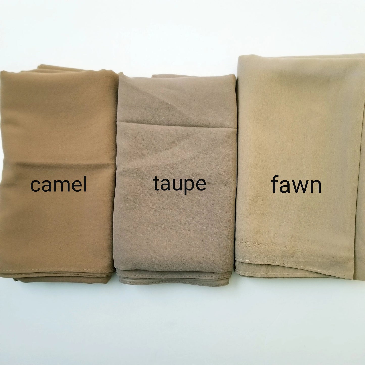 Three folded chiffon hijabs in camel, 'taupe', and 'fawn' on a white background.